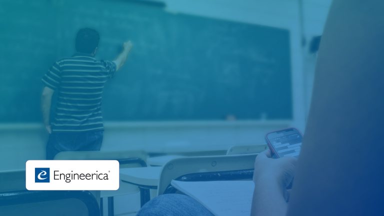Teacher writes on a chalkboard in a classroom while a student uses a smartphone at a desk; blue-tinted image with a logo bottom left.